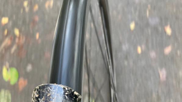 A close-up of a bike wheel from  the top as the bike is being ridden along a path. There's mud on the mudguard
